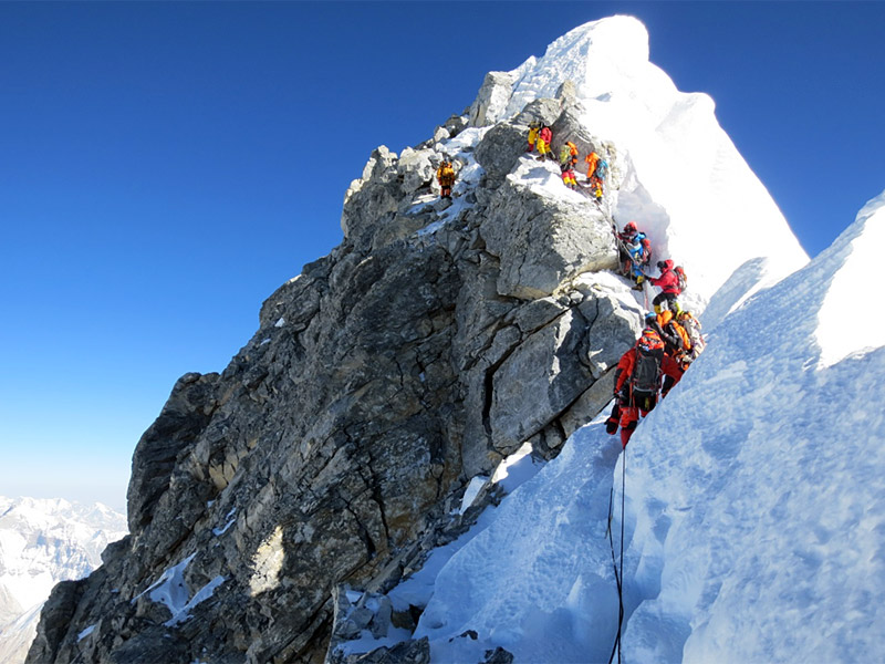 A climber on Everest’s Hillary Step with Sherpas fixing ropes.